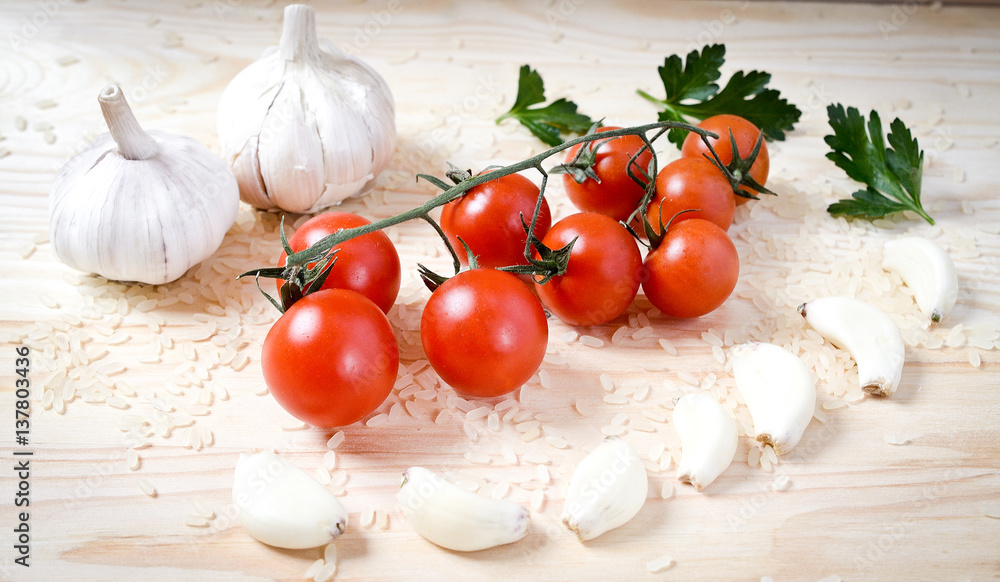 cherry tomatoes on a branch and garlic, parsley on the wooden table. food abstract cherry tomatoes on a branch and garlic, parsley on the wooden table. food abstract