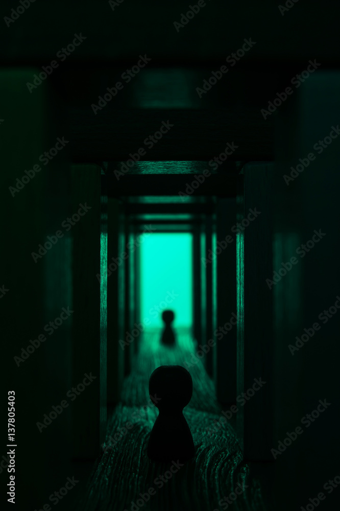 Light at the end of tunnel. A silhouette near the exit from abstract hallway. Two persons walk to the light in the end of the tunnel. Abstract man walking in mystic wooden corridor with bright light.