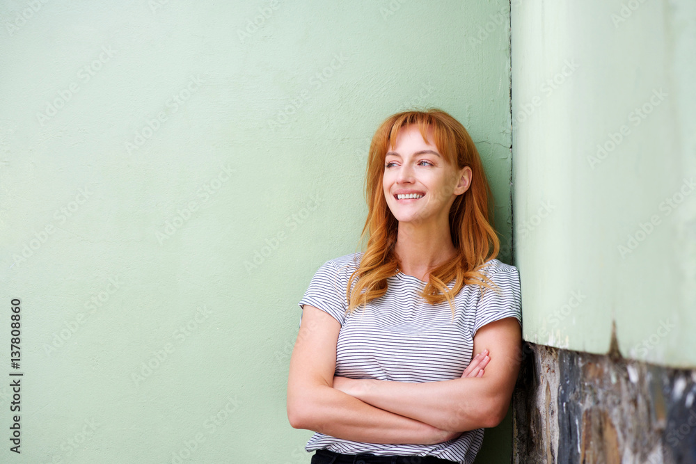 beautiful woman smiling and standing by wall with arms crossed beautiful woman smiling and standing by wall with arms crossed