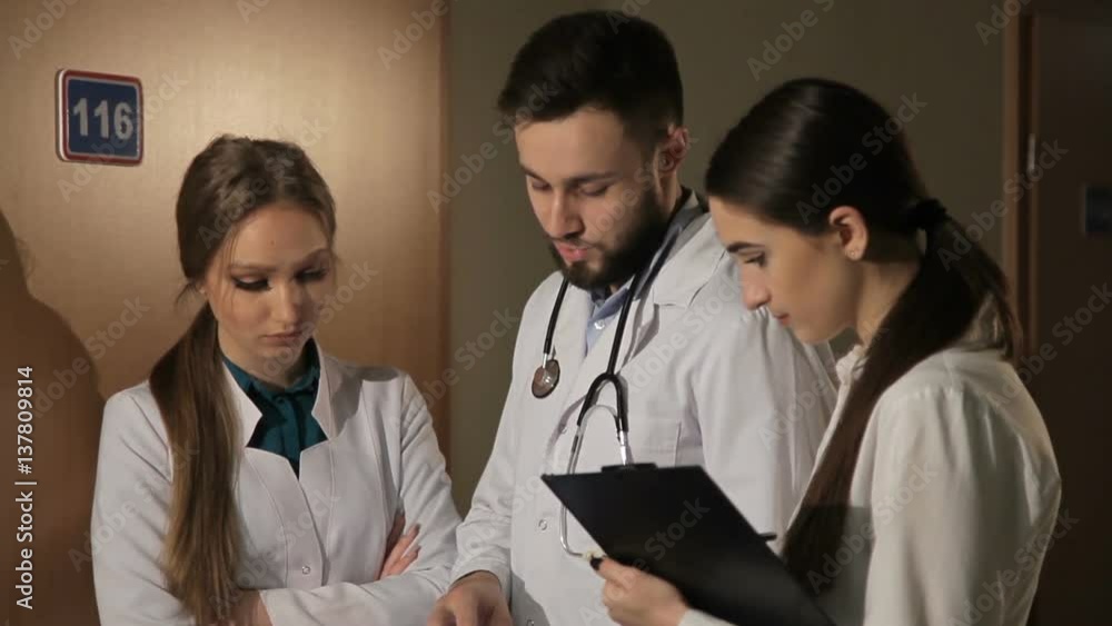 Doctor showing something in his tablet to his medical team Doctor showing something in his tablet to his medical team
