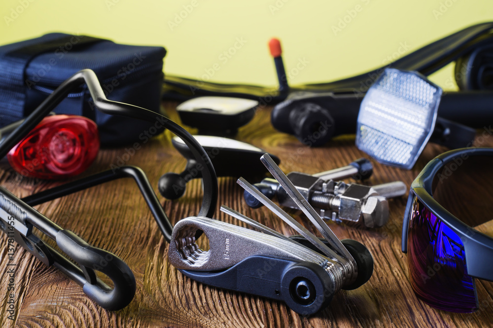 Fototapeta premium Tools and accessories set for cycling. Accessories for bicycles trips: universal screwdriver tool and screws, glasses, bicycle mirror, pump, water holder, speedometer. Bike tools and spares.