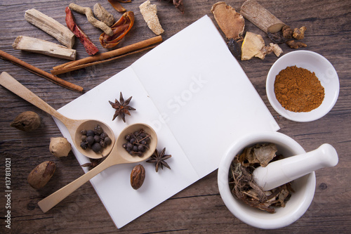 Herbal medicine with white mortar and notebook for on wood table for medical learning