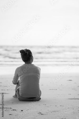 Lovely lady sitting alone on the sand. lonely lovelorn women sit on the beach.Style loneliness.divorce.Style black and white