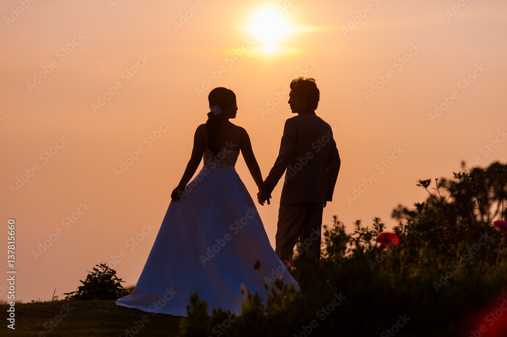 Asian Bride and Groom Standing on Mountain at Sunset