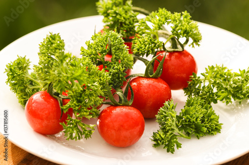 Cherry tomatoes with curled parsley in white plate close up