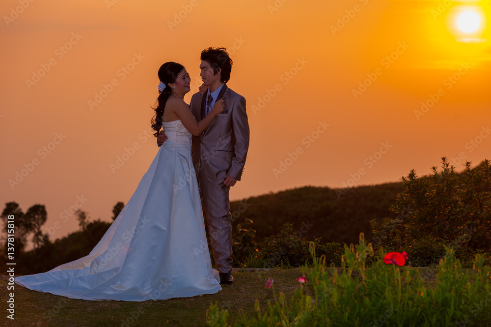 Asian Bride and Groom Standing on Mountain at Sunset Asian Bride and Groom Standing on Mountain at Sunset