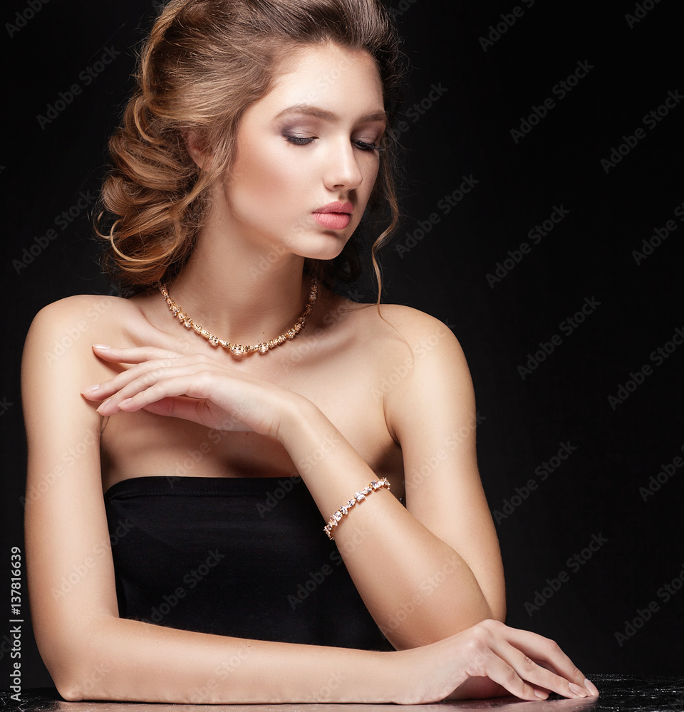Beauty portrait of luxury fashion elegant woman with glamour gold jewellery, curly hairstyle on black background. Accessories and jewelry. Copy space.