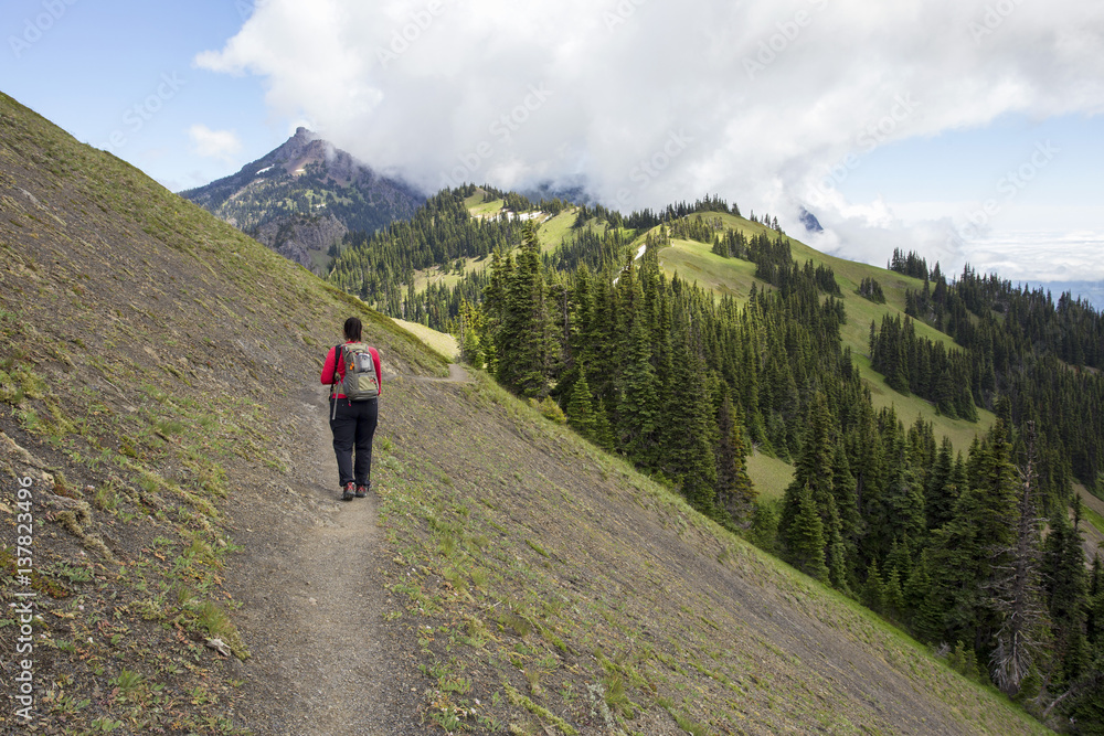 Female hiker on steep mountain ridge trail