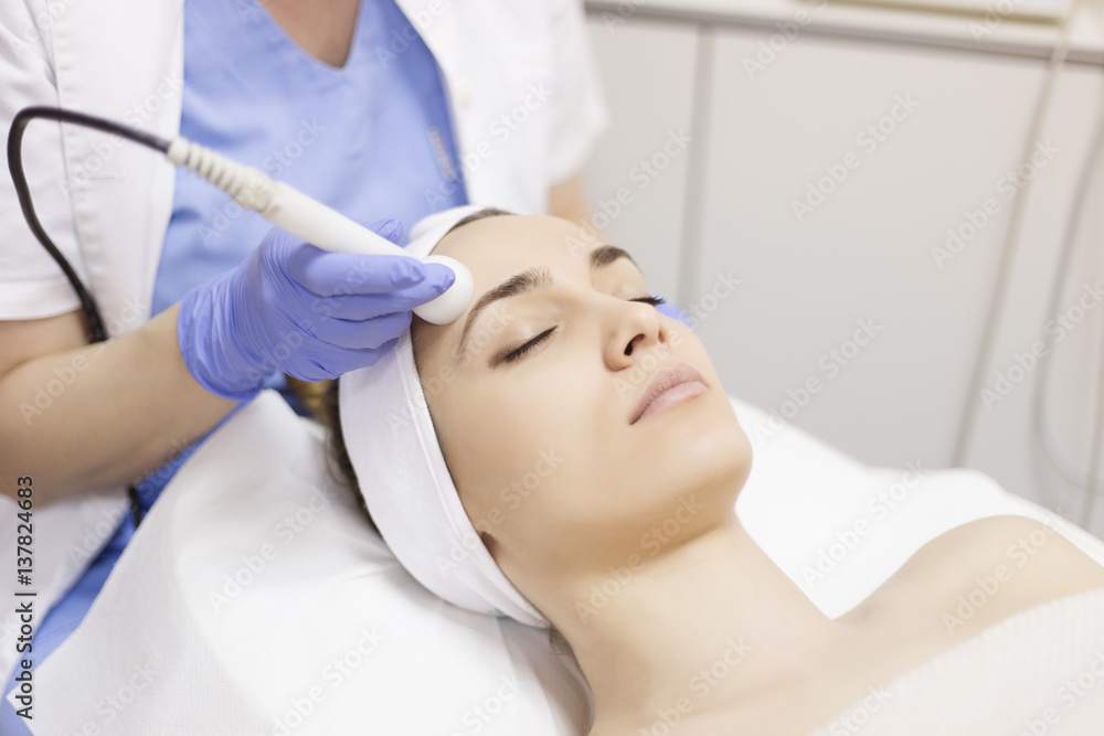 Skin care. Young woman receiving facial beauty treatment. Facial therapy. Anti-aging procedures.