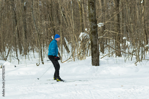 The man on the cross-country skiing in winter forest.