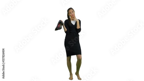 Tired young businesswoman standing barefoot and holding high heels shoes on white background photo