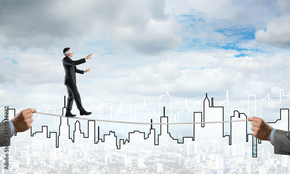 Business concept of risk support and assistance with man balancing on rope Business concept of risk support and assistance with man balancing on rope