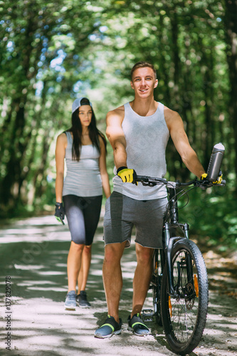 Young Couple Riding Bike In Park