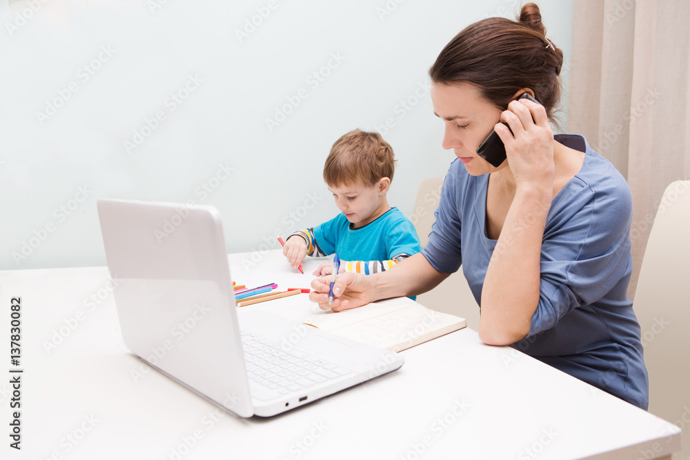 Little boy drawing while his mother is working on a laptop in the home. Mother is a freelancer.
Little boy drawing while his mother is working on a laptop in the home. Mother is a freelancer.
