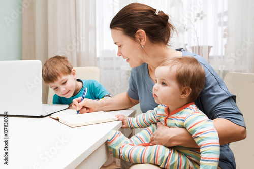 Schilderij op canvas A mother working at home and parenting her two children.