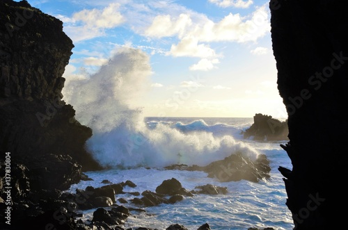 Waves breaking at the cliffs in front of the Ana Kai Tangata Cave close to Hanga Roa in Rapa Nui, Easter Island in Chile, South America photo