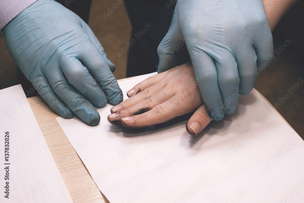 Obraz premium The investigation of the crime. The inspector takes fingerprints of a suspect.