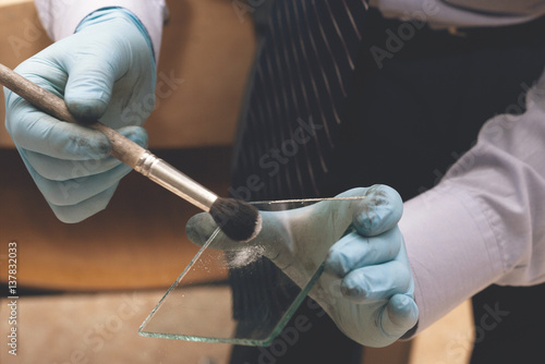 Obraz na płótnie Police forensic expert taking fingerprints from the glass with a special brush. The investigation of the crime. Search for evidence. w salonie