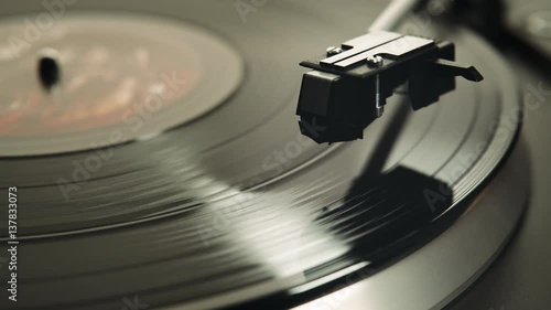 Gramophone and record to listen to. Included gramophone and torque plate close-up on a light background with bright lights. Hand puts needle on vinyl record