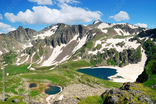  Mountain Lake with clean water and ice in the Caucasus summer. Blue sky with white clouds.