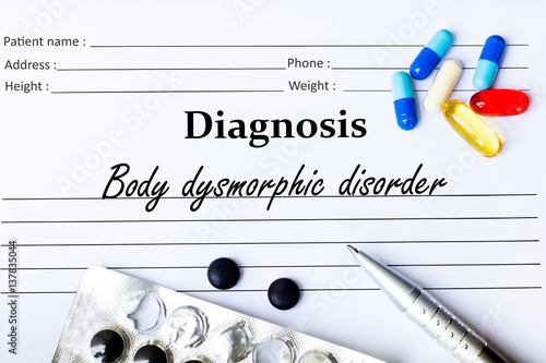 Body dysmorphic disorder -  Diagnosis written on a piece of white paper with medication and Pills