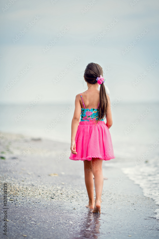 Young girl walking on sandy beach, looking at sea Young girl walking on sandy beach, looking at sea