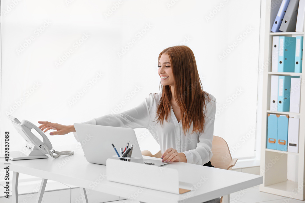 Young businesswoman sitting at office table and speaking by phone Young businesswoman sitting at office table and speaking by phone
