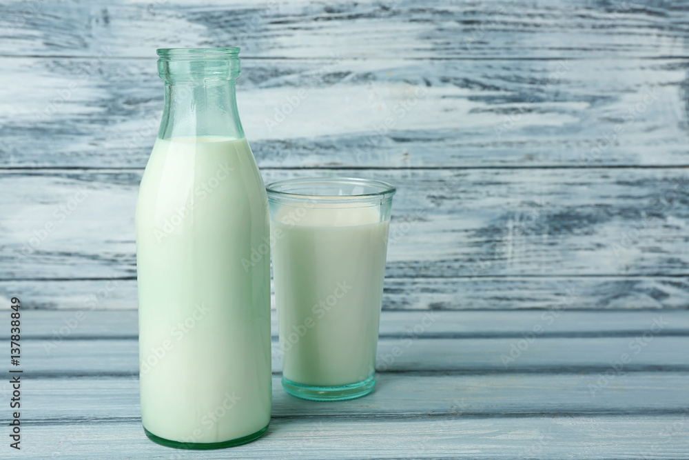 Bottle and glass of milk on wooden background