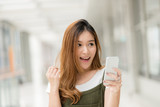 Young beautiful happy Asian girls laugh and smile while having fun with smartphone mobile indoor.