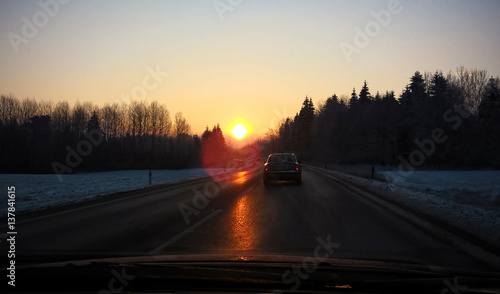 Road with car with sun reflection on frozen surface during winter. Slovakia