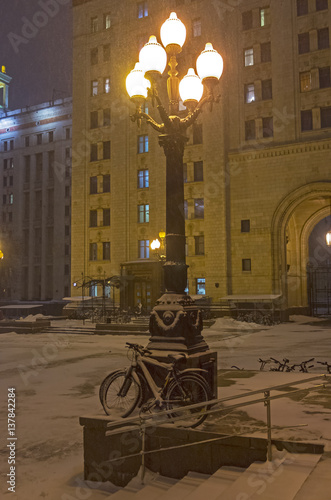 Snow-covered bicycles leaning against the lamppost. photo