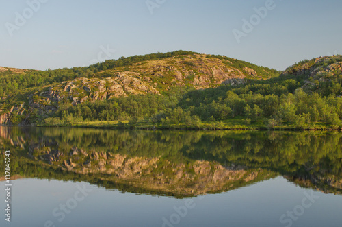 Calm lake in the summer and rocks. © Moroshka