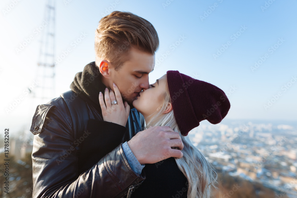 Plakat Young hipster couple in love with black dress walking in the city and kissing. Close up