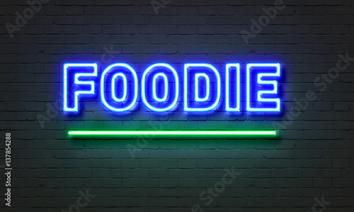 Foodie neon sign on brick wall background. photo