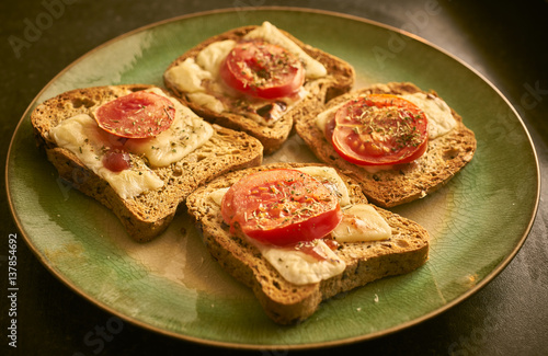 Melted cheese on toast with sliced tomato and herbs