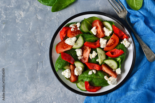 Vegetable salad with tomatoes, spinach and peppers on a concrete, gray background. Top view.