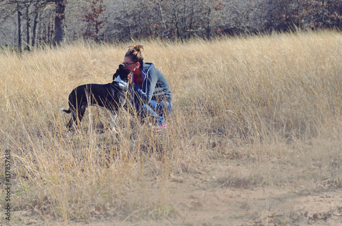 Girl kissing dog in rustic natural field of grass.  Love and affection with man's best friend and person. © ccestep8