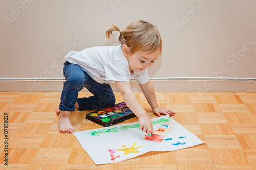 Toddler girl trying to draw with her finger. Kids art