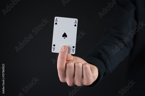 Mann hält ein Ass in der Hand auf schwarzem Hintergrund
