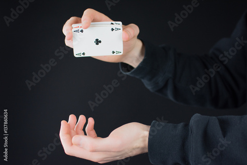 Mann hält ein Ass in der Hand und lässt es fallen