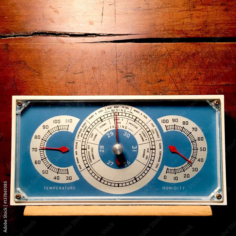Naklejka premium Vintage blue barometer on weathered wood background.