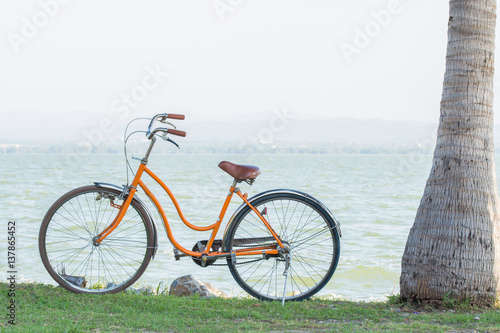 Orange bicycle with the backdrop of the mountains and the sea with warm sunshine.