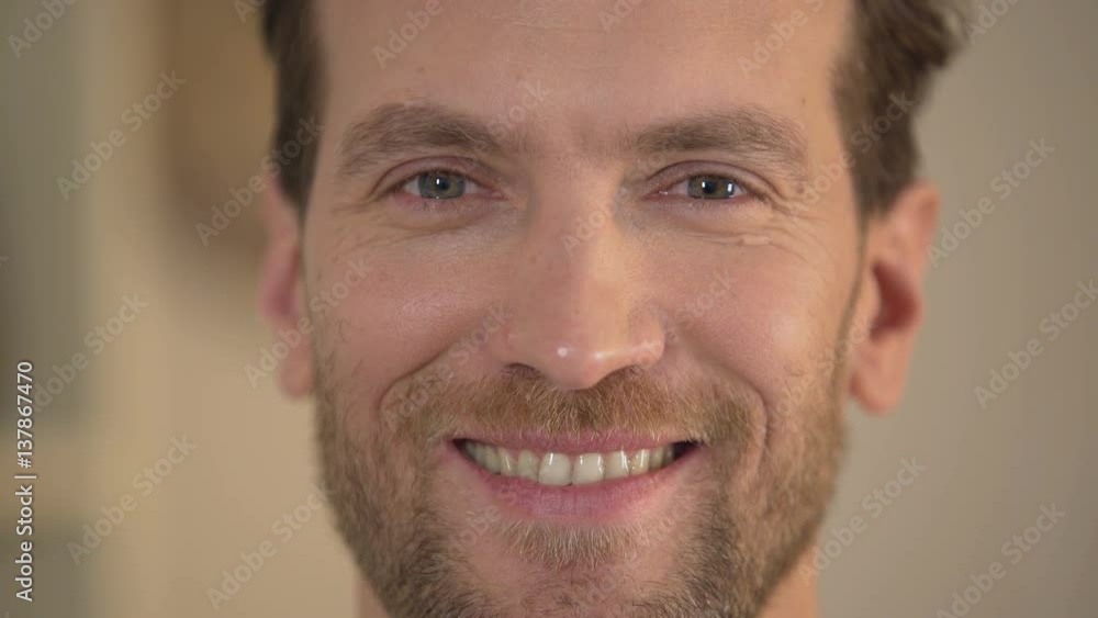 Healthy smile of handsome young man looking into camera, male face close-up Healthy smile of handsome young man looking into camera, male face close-up