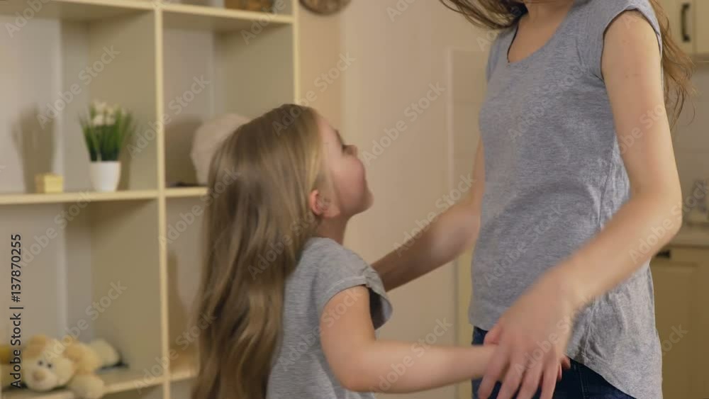 Happy smiling girl hugging, jumping and playing with her mother or big sister Happy smiling girl hugging, jumping and playing with her mother or big sister