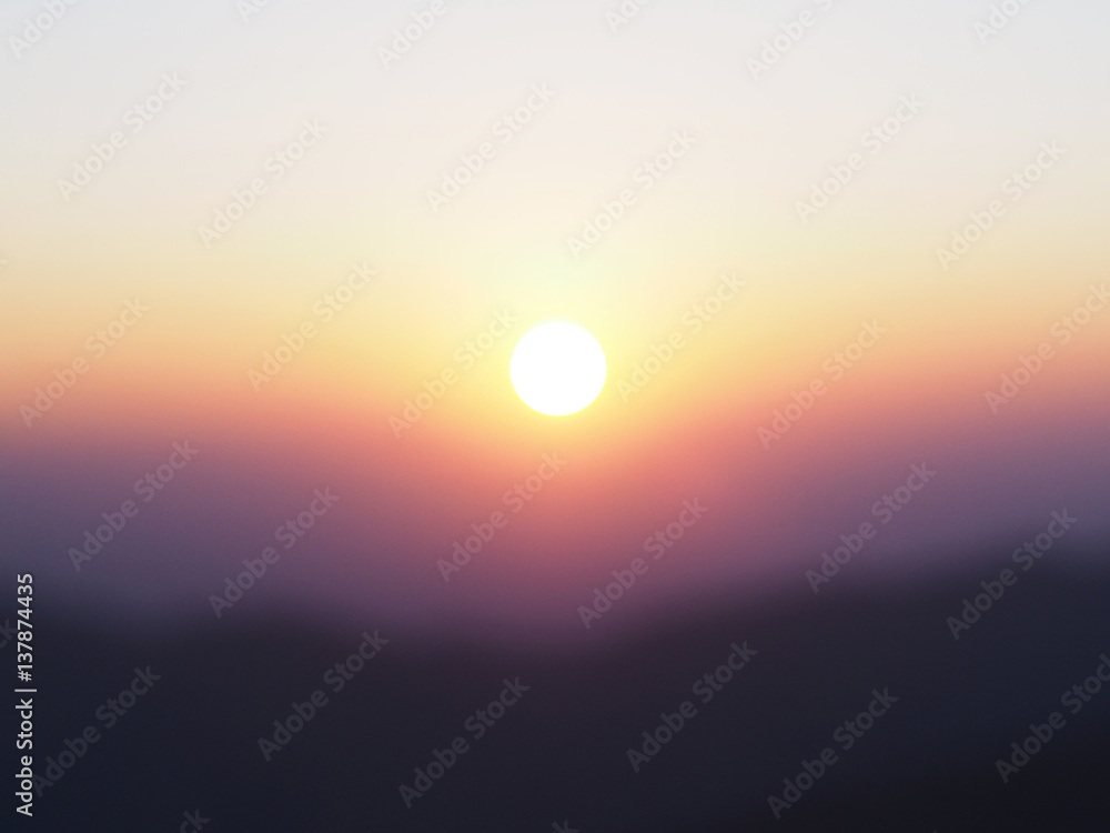 Sun at sunrise with blurry mountain and sky background