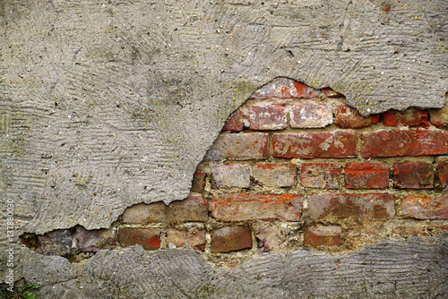 A whole in the concrete roughcast that reveals a brick wall.