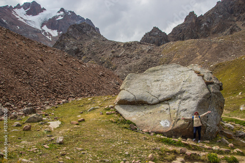 Woman are standing in the mountains near a giant stone name Zimin, Tien Shan mountains near Shymbulak ski resort, Almaty, Kazakhstan photo