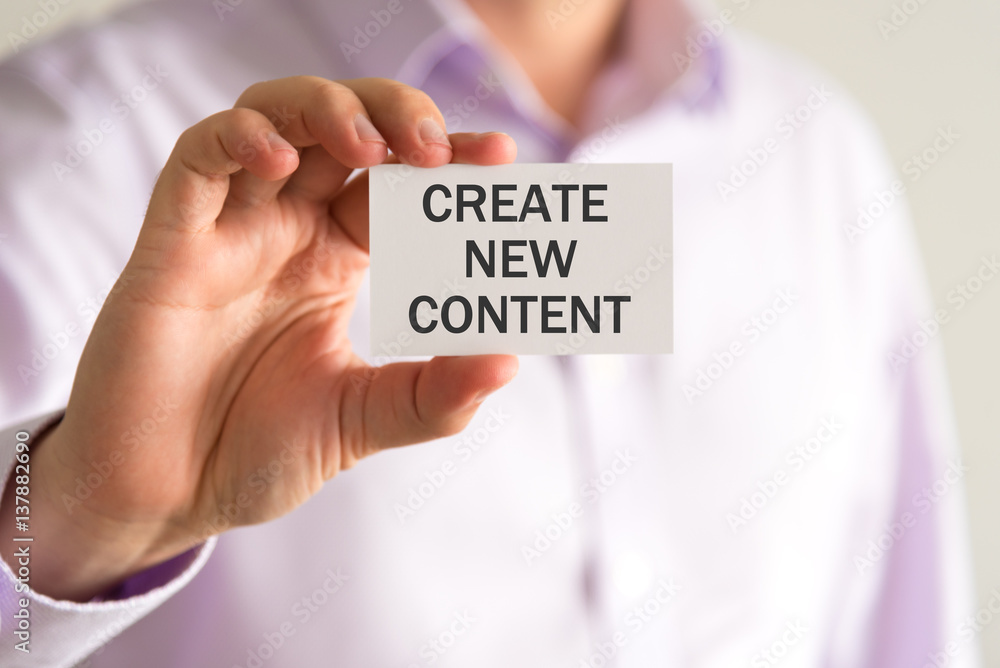 Businessman holding a card with text CREATE NEW CONTENT Businessman holding a card with text CREATE NEW CONTENT