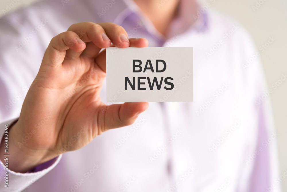 Businessman holding a card with text BAD NEWS Businessman holding a card with text BAD NEWS