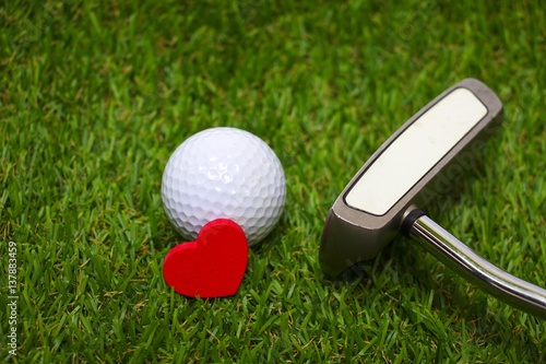 Golf ball with red heart shape are on green course. Idea for golfer's love concept.